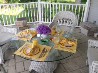 Porch table with a setting and flower centerpiece